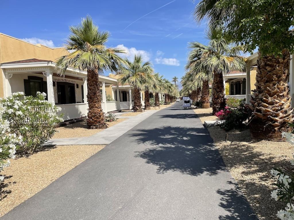 Cottages and palm trees line a road at The Ranch at Death Valley under a blue sky while staying in Death Valley