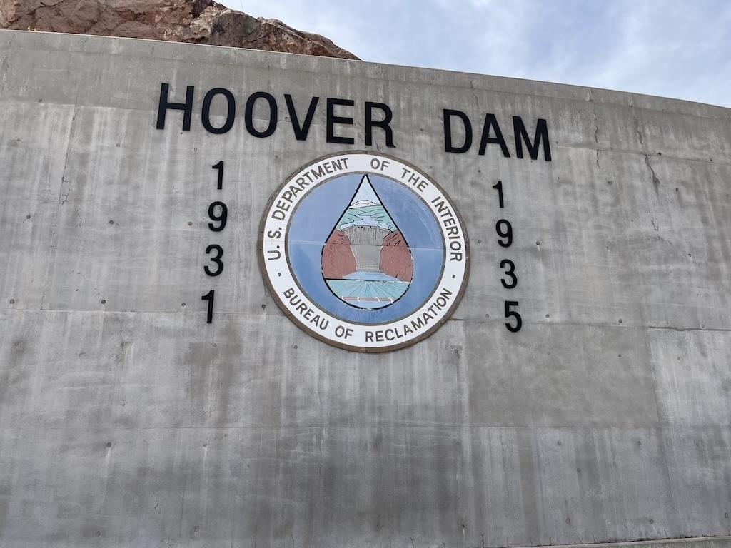 Visiting the Hoover Dam wall with emblem lettering that says built 1931 to 1935
