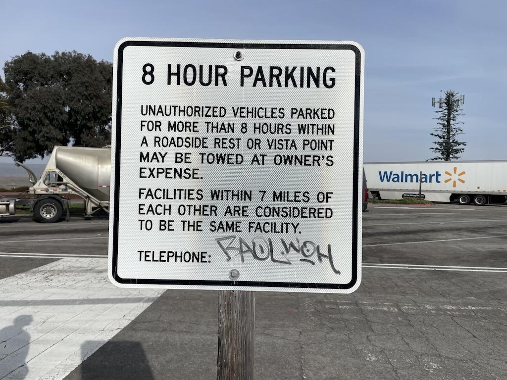 Parking sign at rest area that says vehicles parked more than 8 hours will be towed