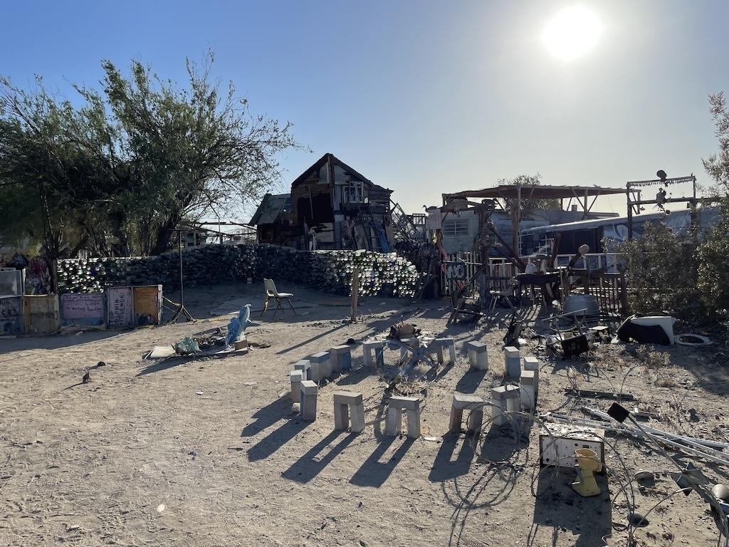 Art installations of glass bottle, bricks, and other items in front of a house in East Jesus, Slab city