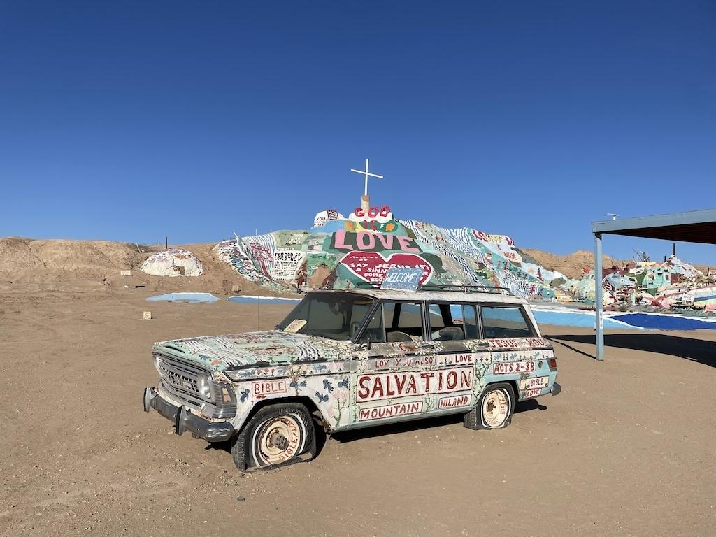 Painted car that is decorated by artists in front of Salvation Mountain in Slab City