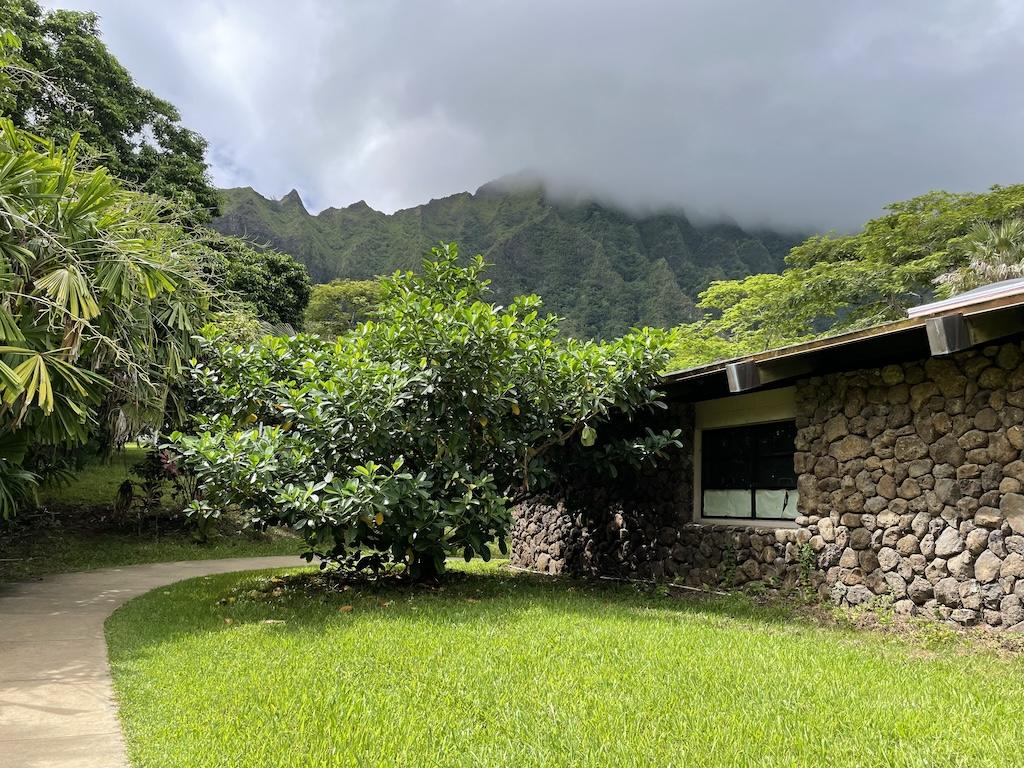 View at Ho’omaluhia Botanical Garden of path behind the visitor’s center and view of mountains with clouds 