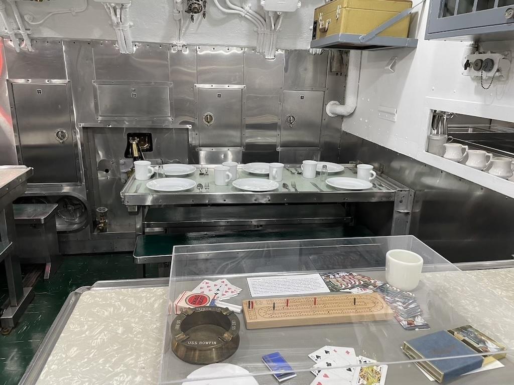 Inside the USS Bowfin kitchen with plates and games under glass, at submarine museum at Pearl Harbor 