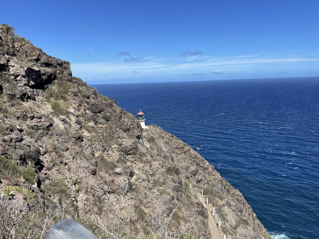 View of Makapu'u Lighthouse in the distance on the side of a cliff in Oahu, Hawaii with ocean in the background