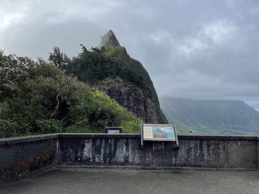 Mountains with trees and sign telling of the history of Nu’uanu Pali Lookout in Ohau, Hawaii