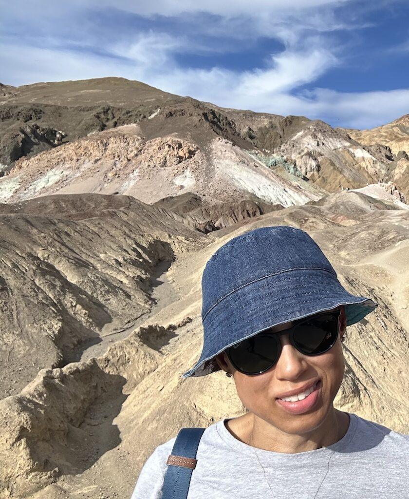 Luna smiling to the camera with Artists Palette colorful rocks in the background at Death Valley National Park, California