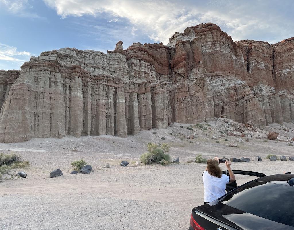 Woman taking a picture of the scenery of tall mountainous rocks on at Death Valley, in California.