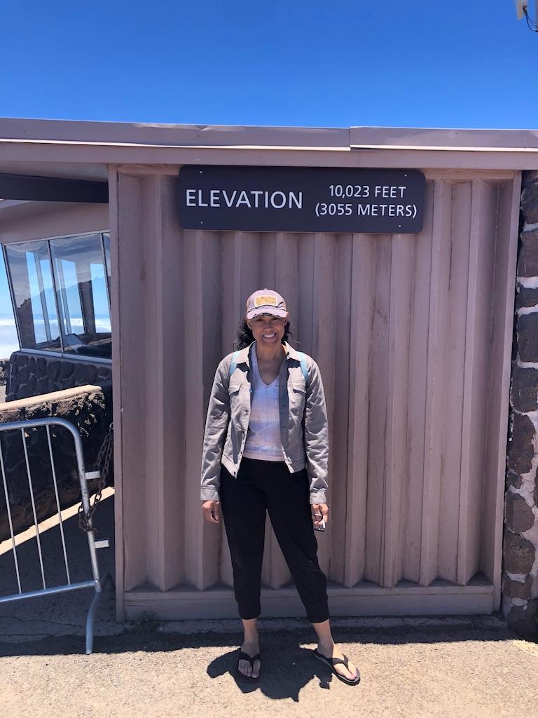 Luna smiling to the camera standing in front of the Haleakala National Park visitor’s center where the elevation is 10,023 feet