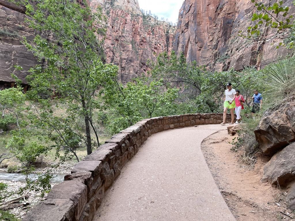People walking on the Riverside Walk path in the distance oat Zion National Park, mountains and trees in the background