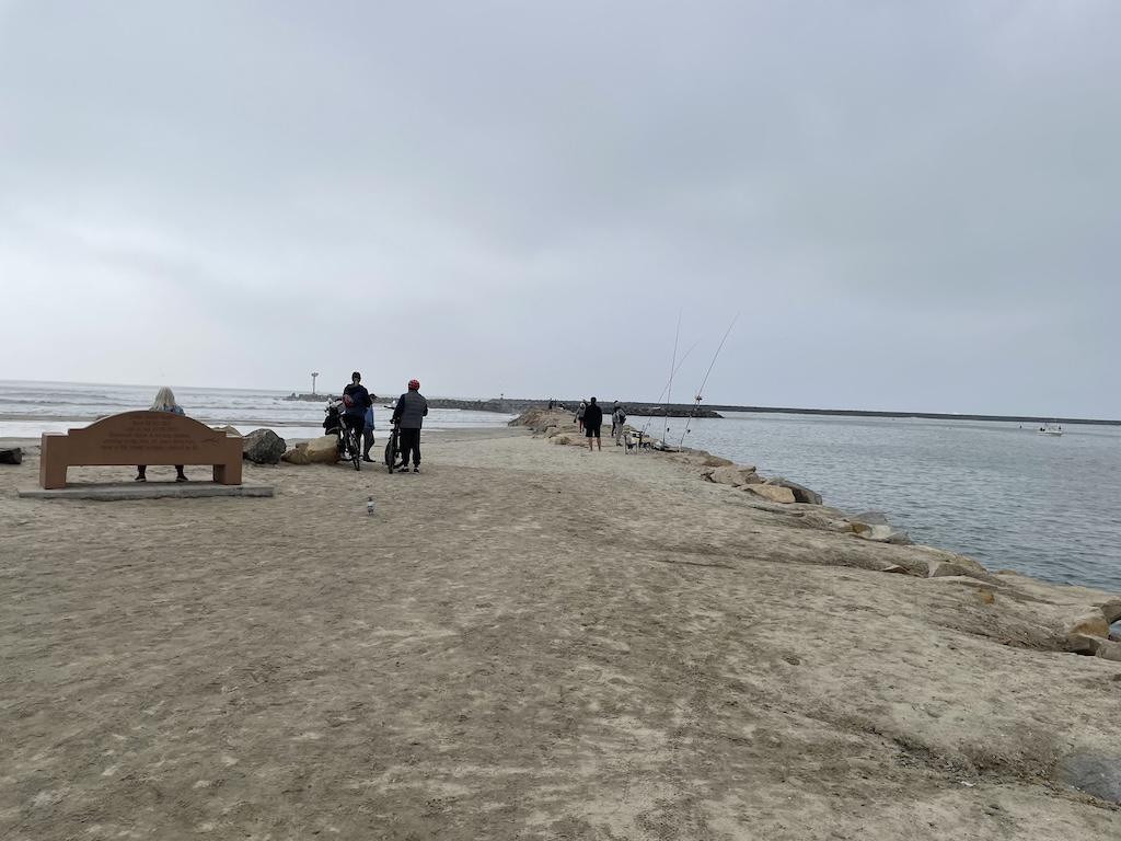 People walking, talking, relaxing, and fishing off the pier at Oceanside Harbor in California