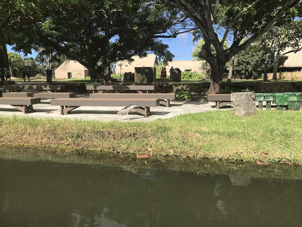 Seating for an island presentation at the Polynesian Cultural Center with huts in the background, in Oahu, Hawaii
