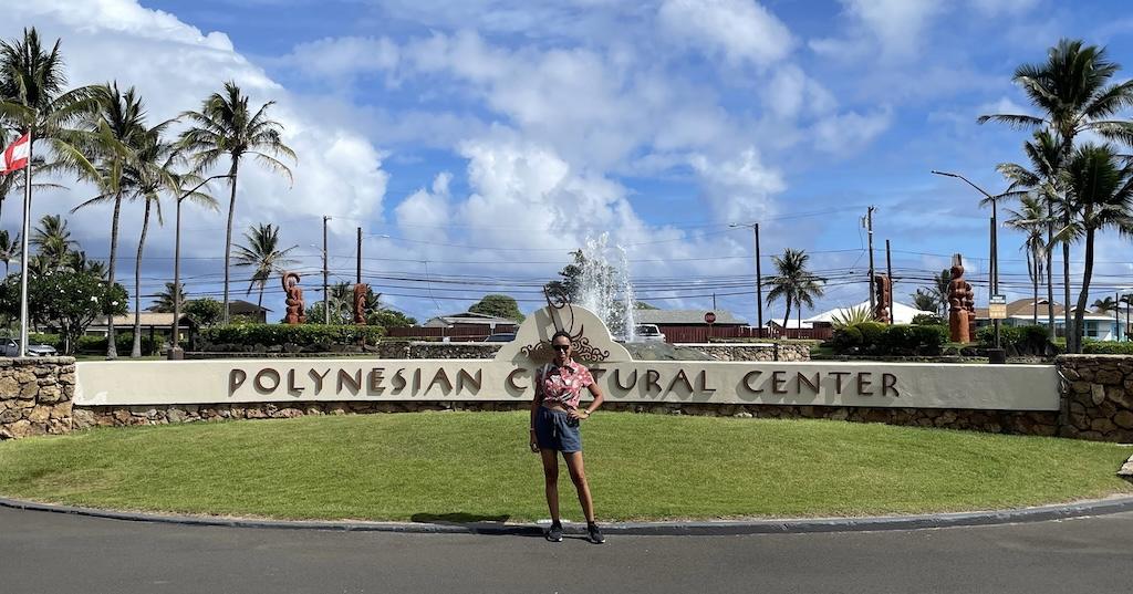 Luna smiling to the camera and standing in front of the Polynesian Cultural Center entrance in Oahu, Hawaii