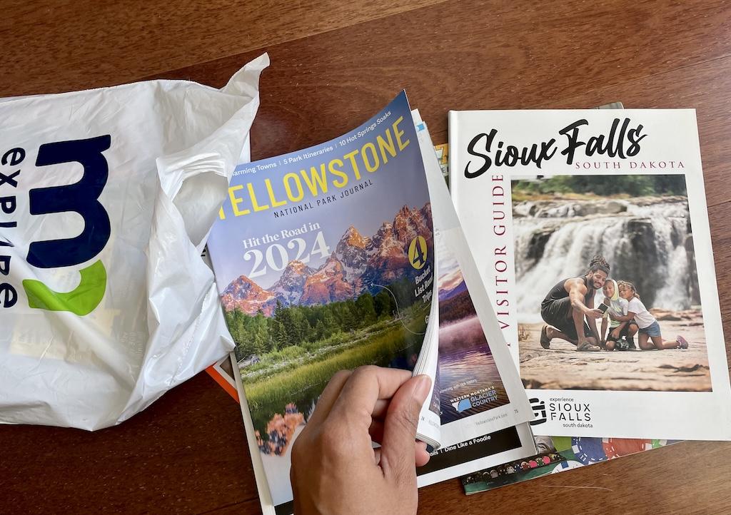 Luna’s hand flipping the cover of a Yellowstone magazine with other books and guides in the background