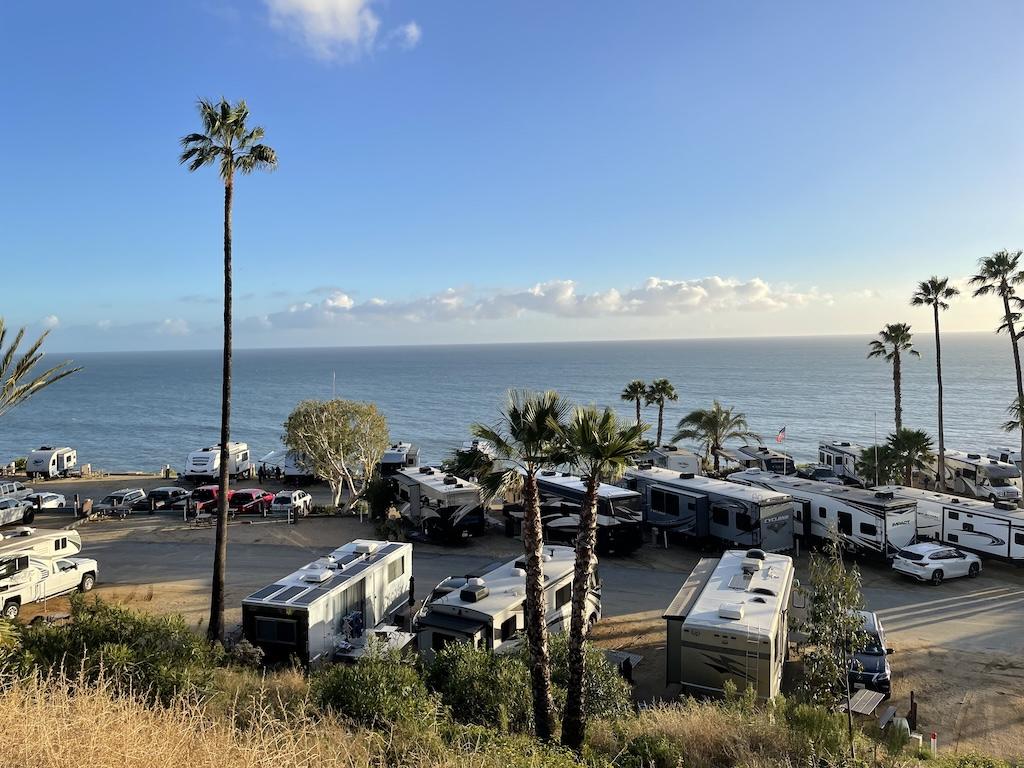 Top view of RVs and vehicles in parking spots at Surf Outpost with oceanview in Malibu, California