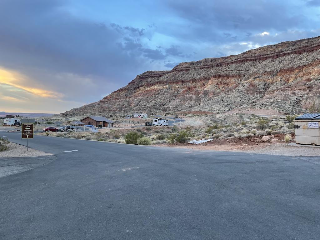 View of red rock formations next to the RVs and cars in the distance at Quail Creek State Park Campground in Hurricane, Utah.