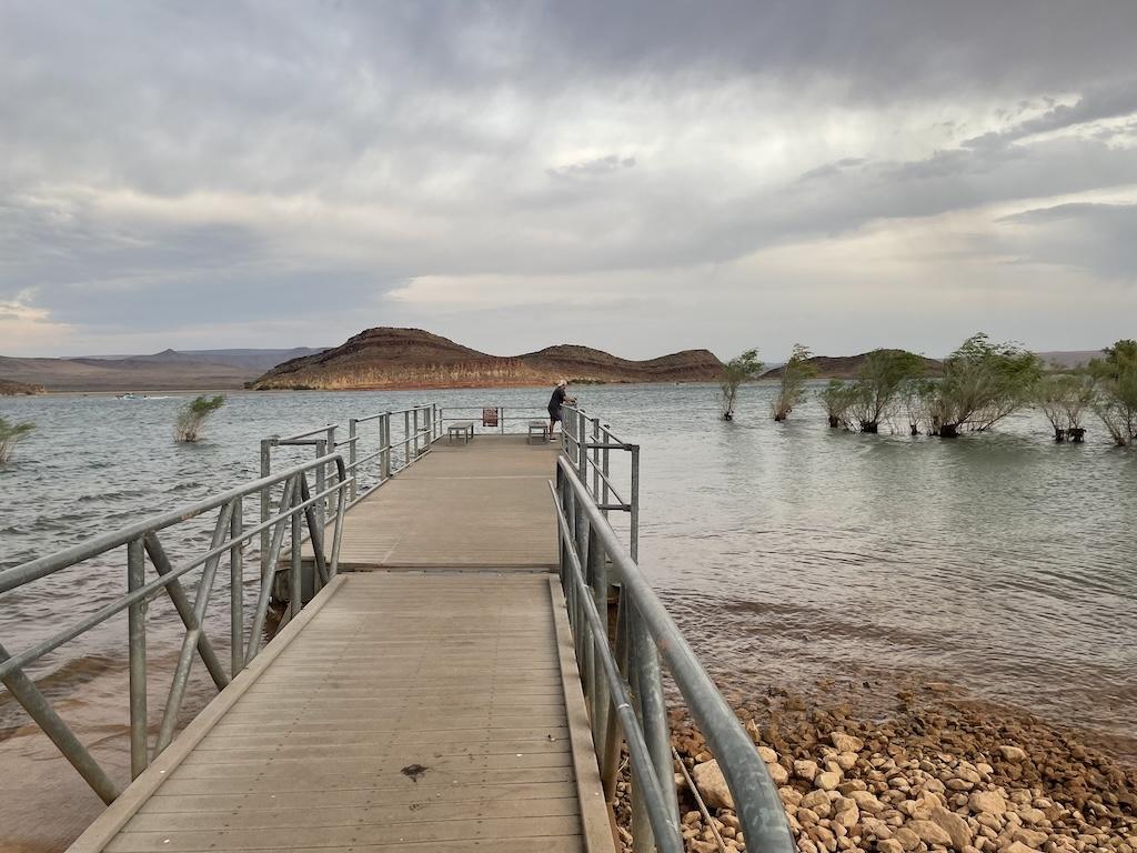 In the distance, a man fishing off the pier at Quail Creek State Park in Hurricane, Utah.