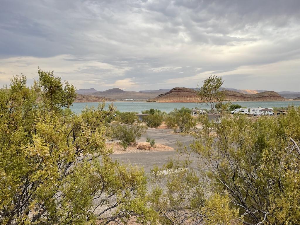Luna's view of the lake, mountains, and campers from a distance at while camping at Quail Creek State Park Campground in Hurricane, Utah.