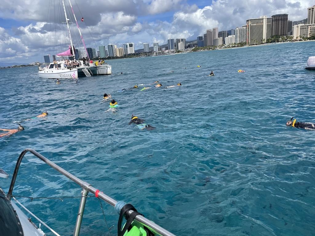 People swimming and snorkeling near catamaran at Turtle Bay in Oahu, Hawaii