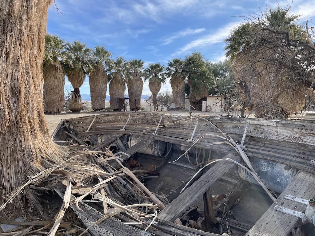 Old boat with palm trees in the background at Soda Springs off Zzyzx Road in California
