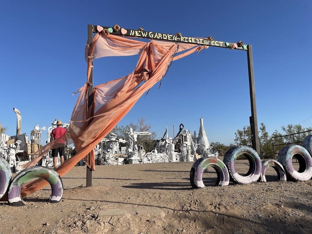 Garden exhibit in East Jesus with a man looking around in the distance, in Slab City, California