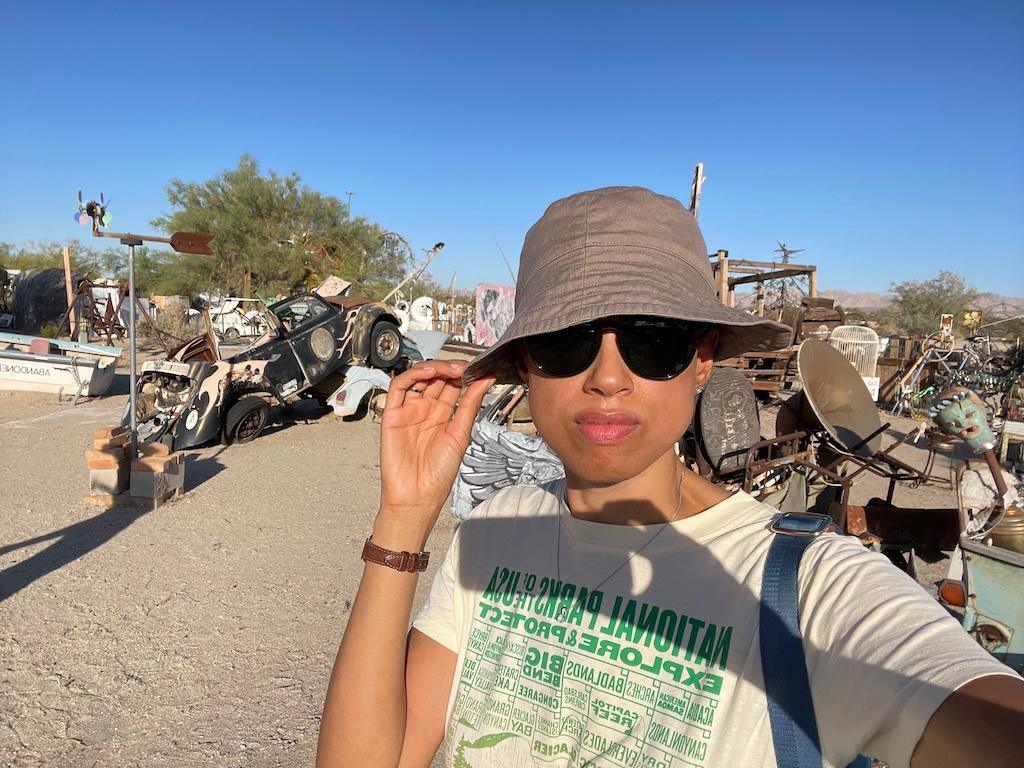 Close up selfie Luna took while visiting Slab City with the Easy Jesus art exhibits in the background