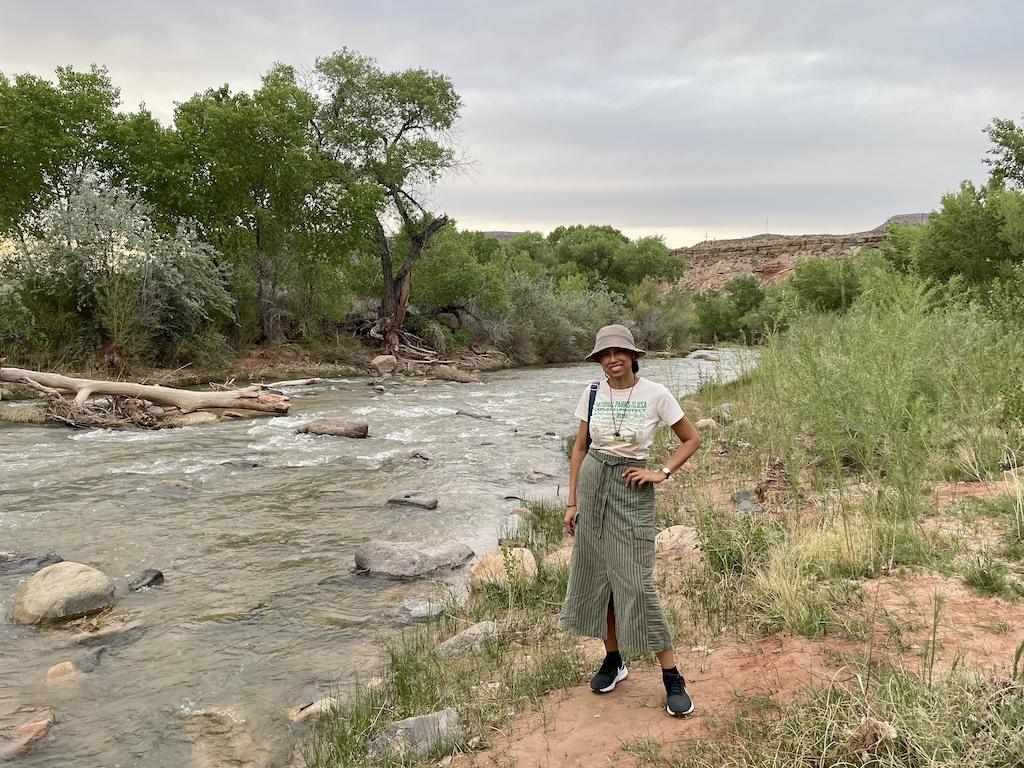 Luna smiling to the camera standing next to the Virgin River at Zion River Resort in Utah