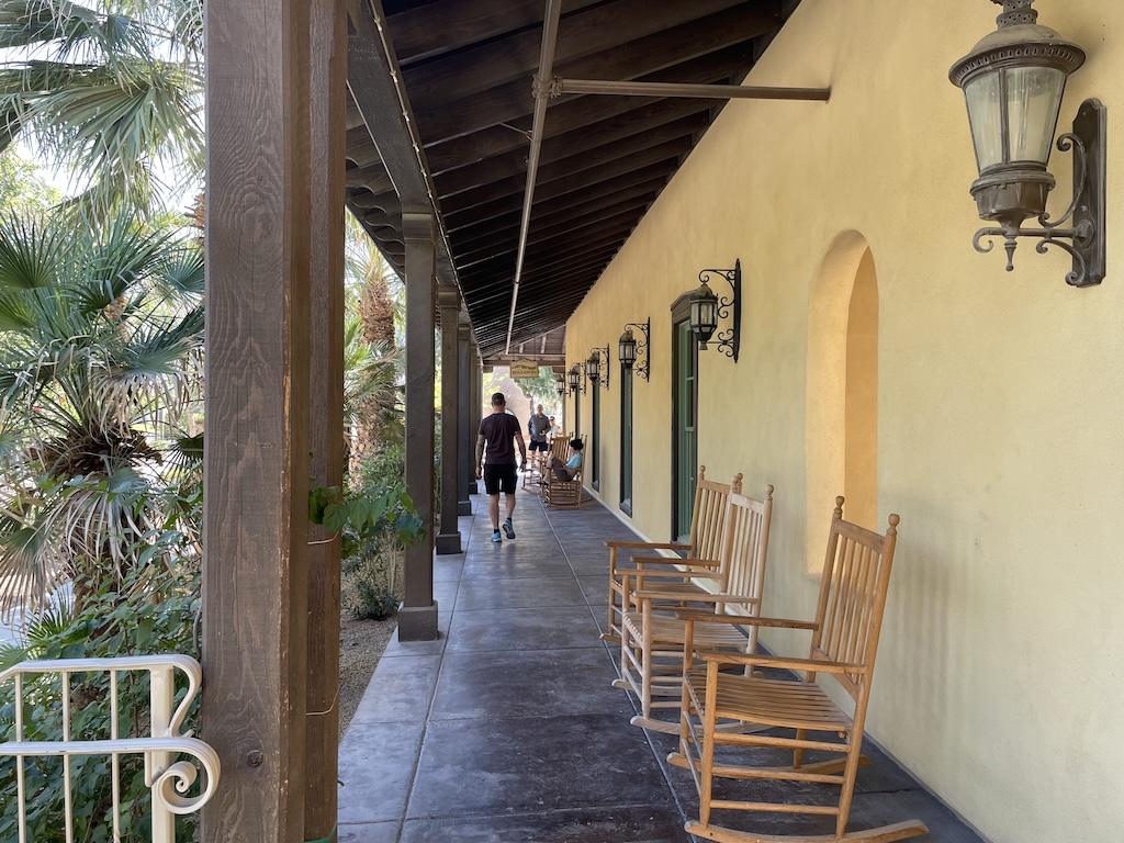 Man walking towards the general store in a hallway with rocking chairs at the Ranch at Death Valley, in Death Valley National Park, California