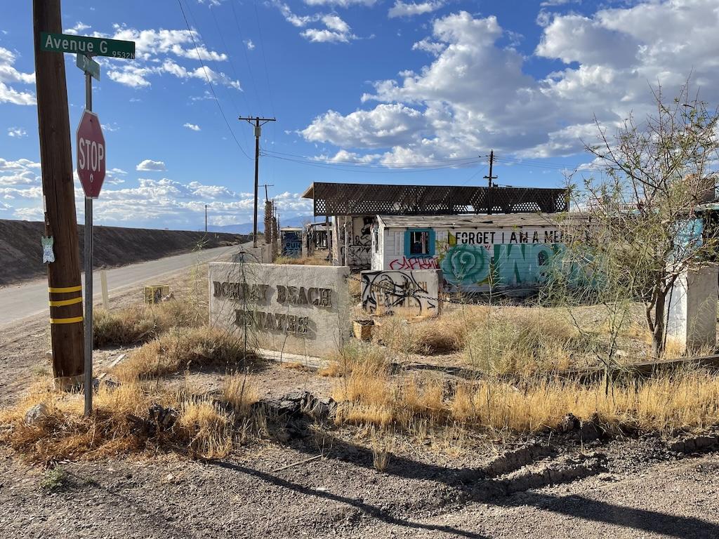 The Bombay Beach estates sign with houses with graffiti in the background near the Salton Sea in California