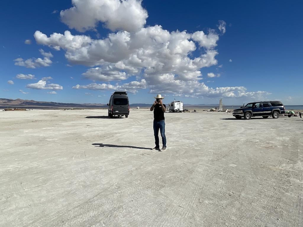 Man holding camera up to his face with camper van in background