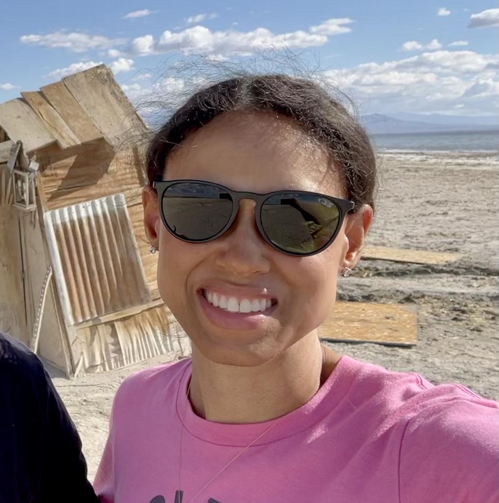 Selfie of Luna smiling to the camera in front of an art exhibit at Bombay Beach on the Salton Sea in California