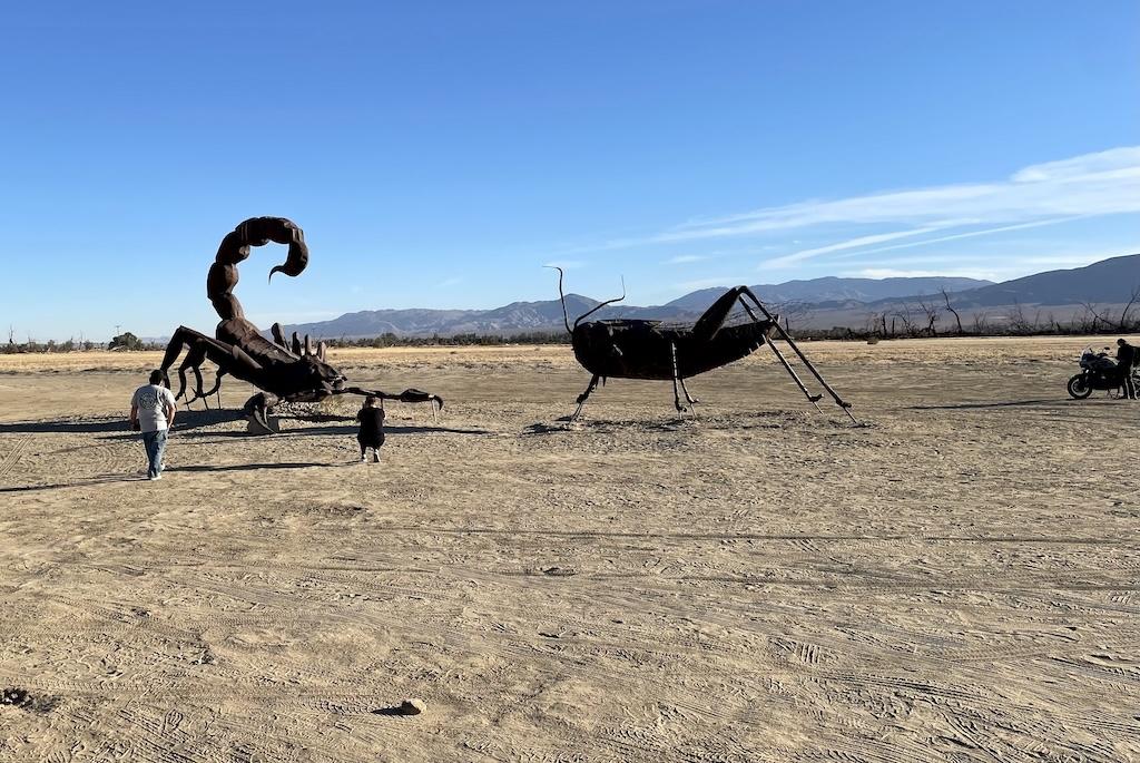 Giant cricket and scorpian sculptures with people taking pictures at Galleta Meadows in Anza-Borrego, California