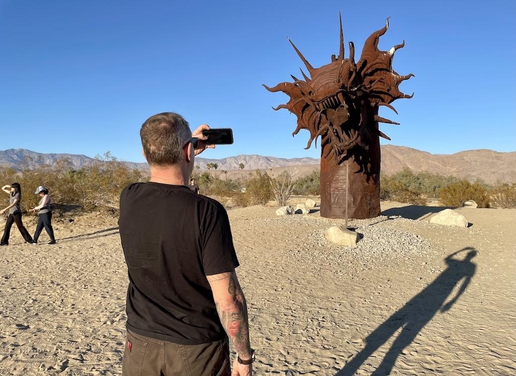 Man taking a picture of the serpent metal sculpture at Galleta Meadows in Anza-Borrego, California
