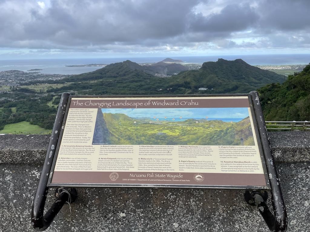 View of ocean and landscape with sign at Nu’uanu Pali Lookout, in Oahu