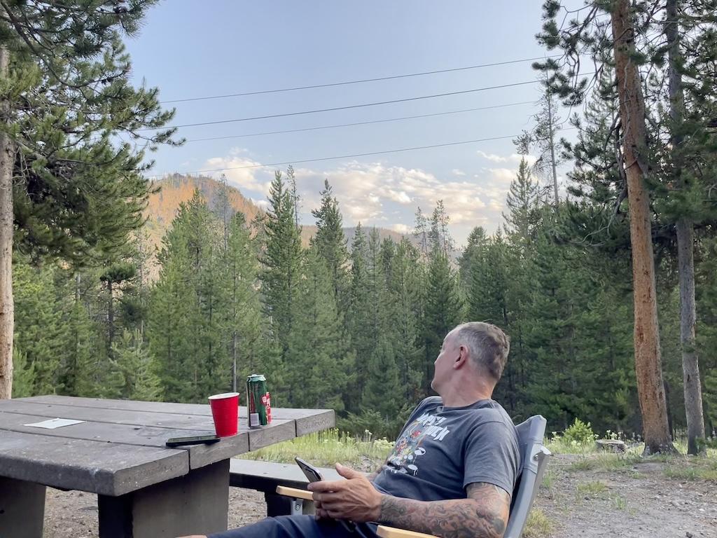 Man relaxing at picnic table with drink at Madison Campground in Yellowstone National Park, Wyoming