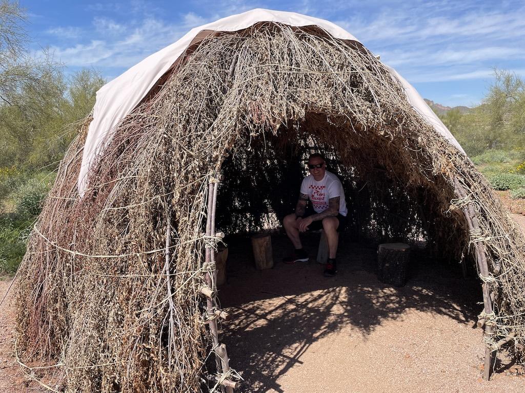 Man smiling and sitting in Apache hut at the Superstition Mountain Museum in Arizona