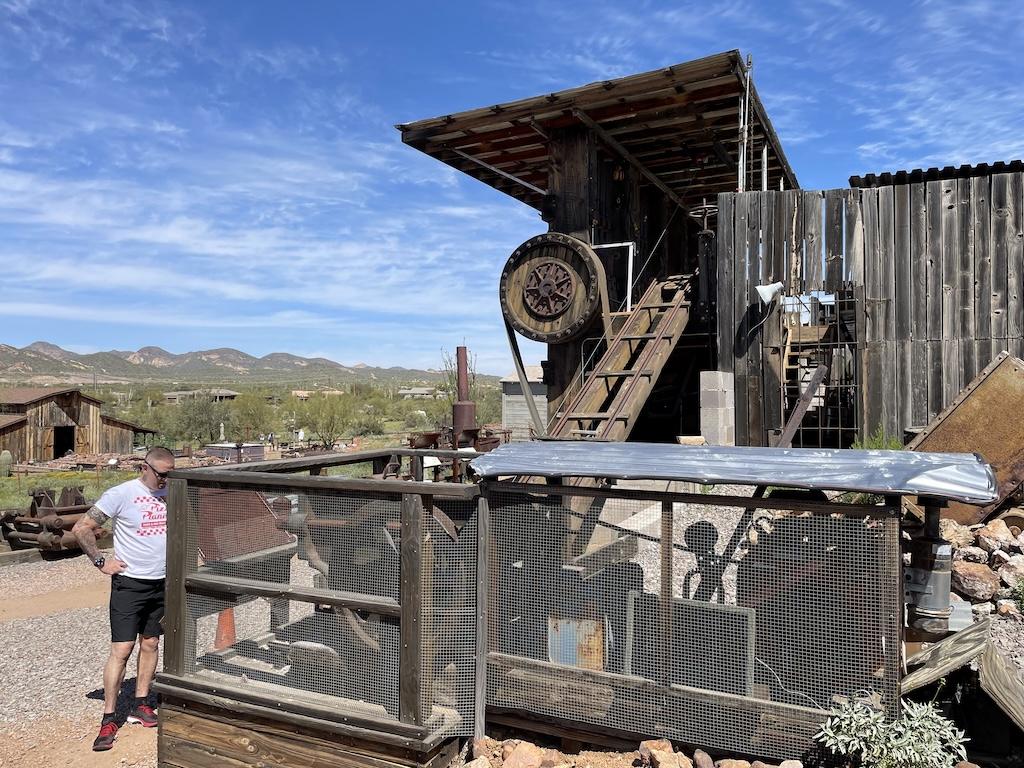 Man looking at mining equipment and tools by the stamp ore mill at the Superstition Mountain Museum in Arizona