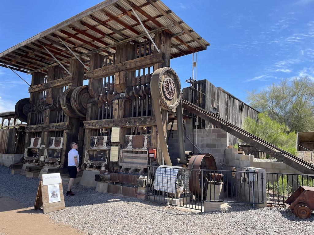 Man looking at the stamp ore mill at the Superstition Mountain Museum in Arizona