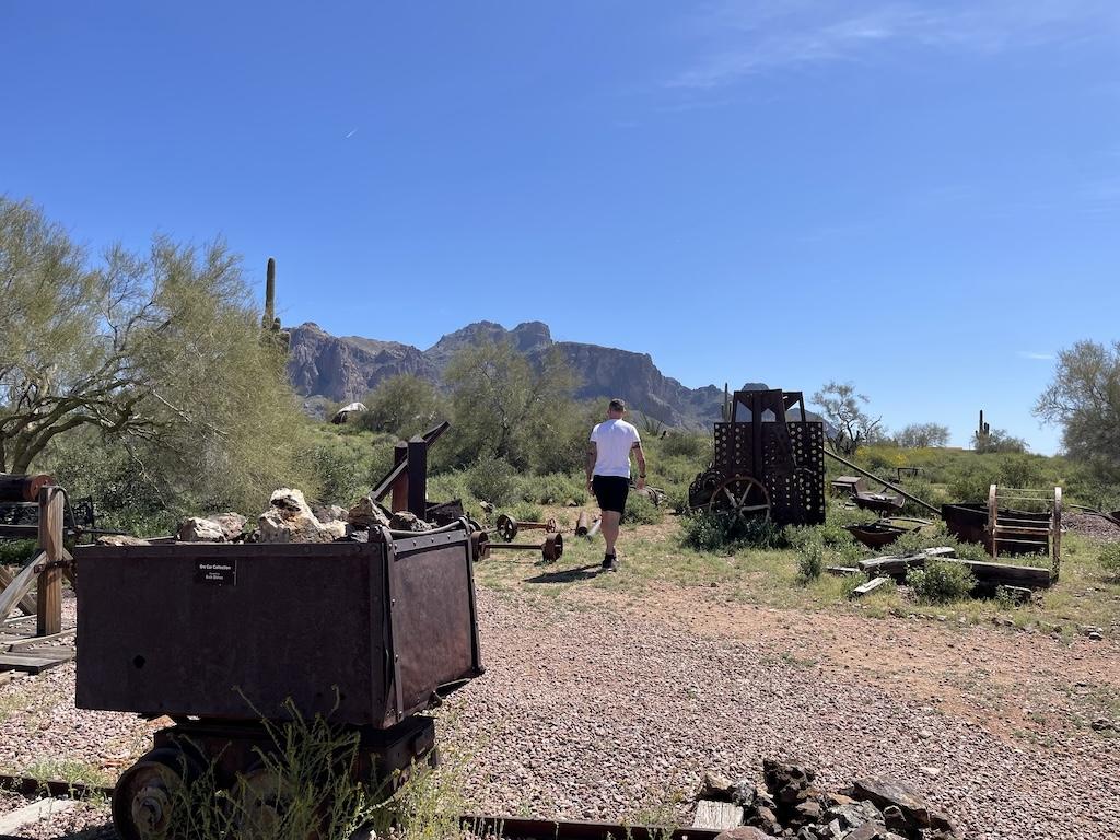 Man walking around mining equipment and tools at the Superstition Mountain Museum in Arizona