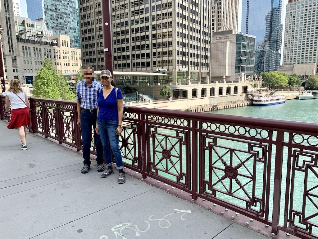 Luna smiling to the camera while standing on a bridge over the Chicago River with buildings in the background in Illinois