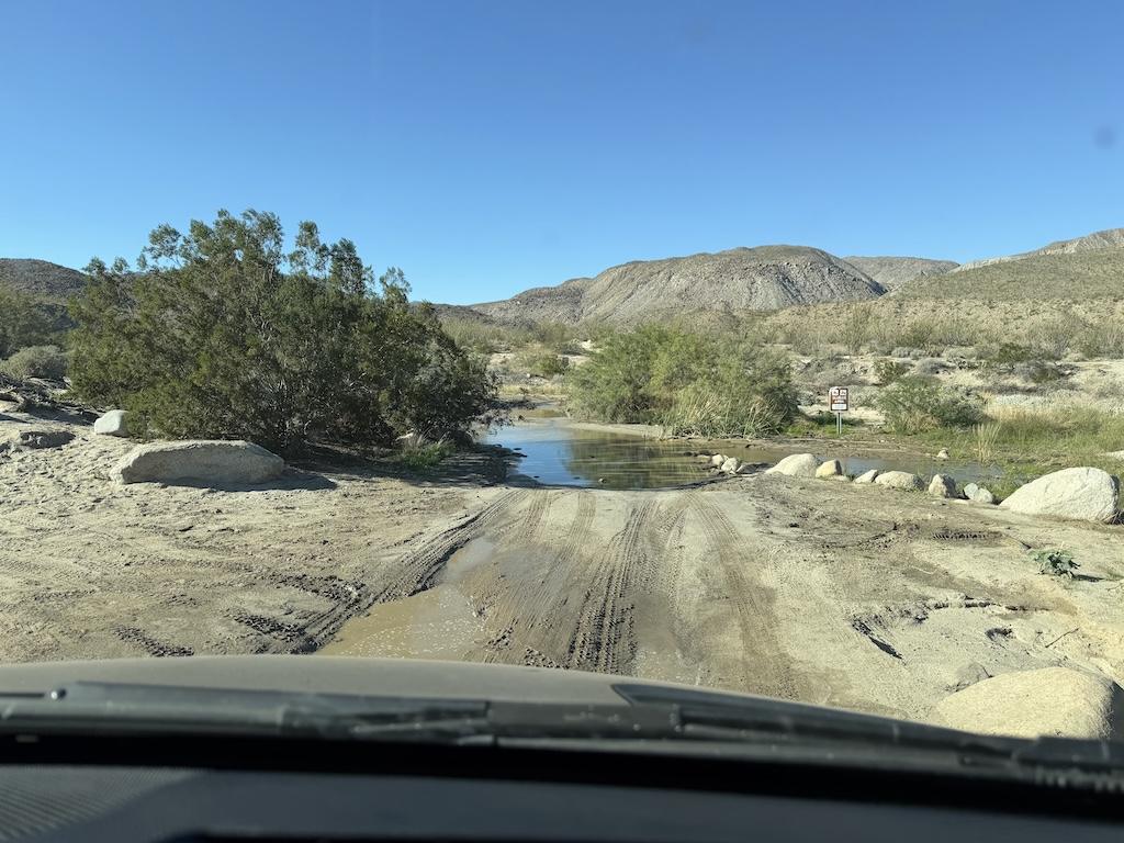 View from camper van driving Coyote Canyon Road with water washed over, Anza-Borrego Desert State Park in California.