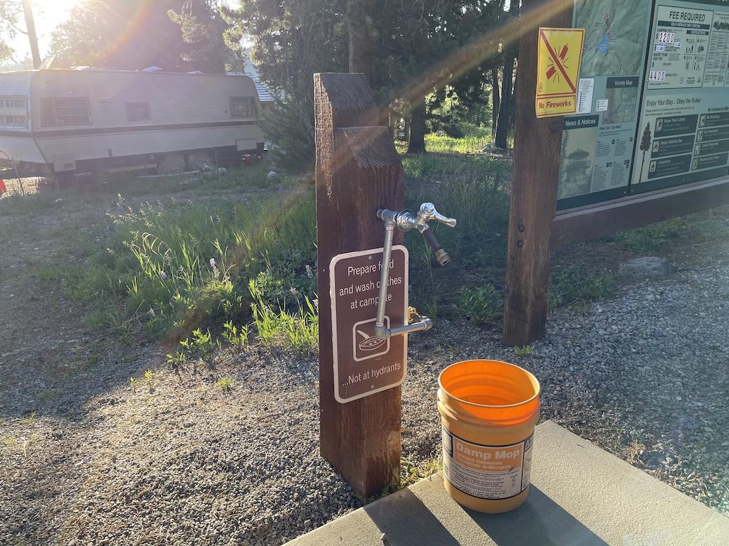 View of water hydrant and bucket, RV in background, at Lakeview Bighorn Campground, Wyoming