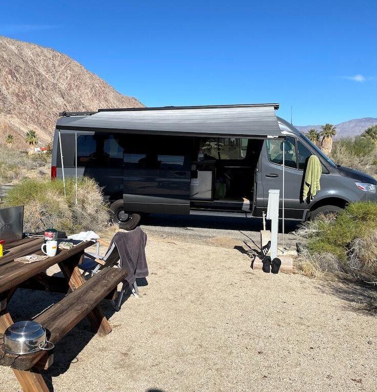 Man cooking on the picnic table while van camping at Borrego Palm Canyon Campground in Anza-Borrego, California