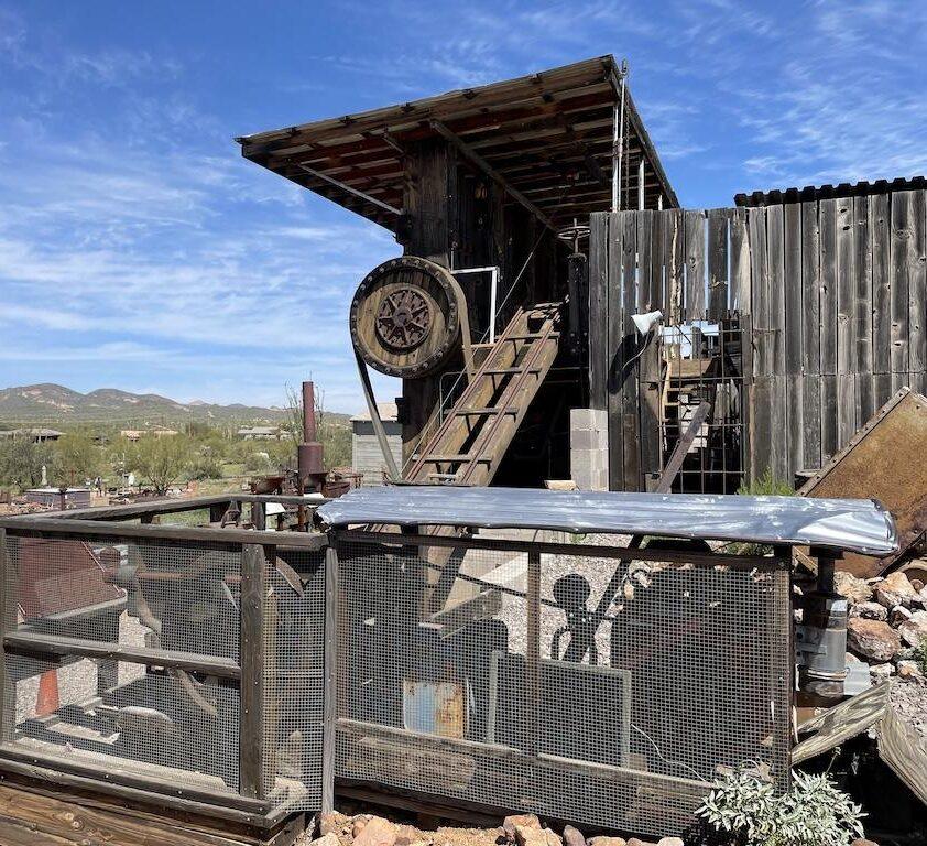 Man looking at mining equipment and tools by the stamp ore mill at the Superstition Mountain Museum in Arizona