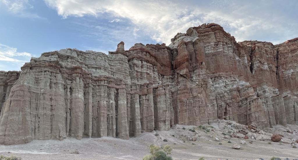Woman taking a picture of the scenery of tall mountainous rocks on at Death Valley, in California.