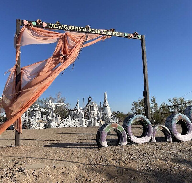 Garden exhibit in East Jesus with a man looking around in the distance, in Slab City, California