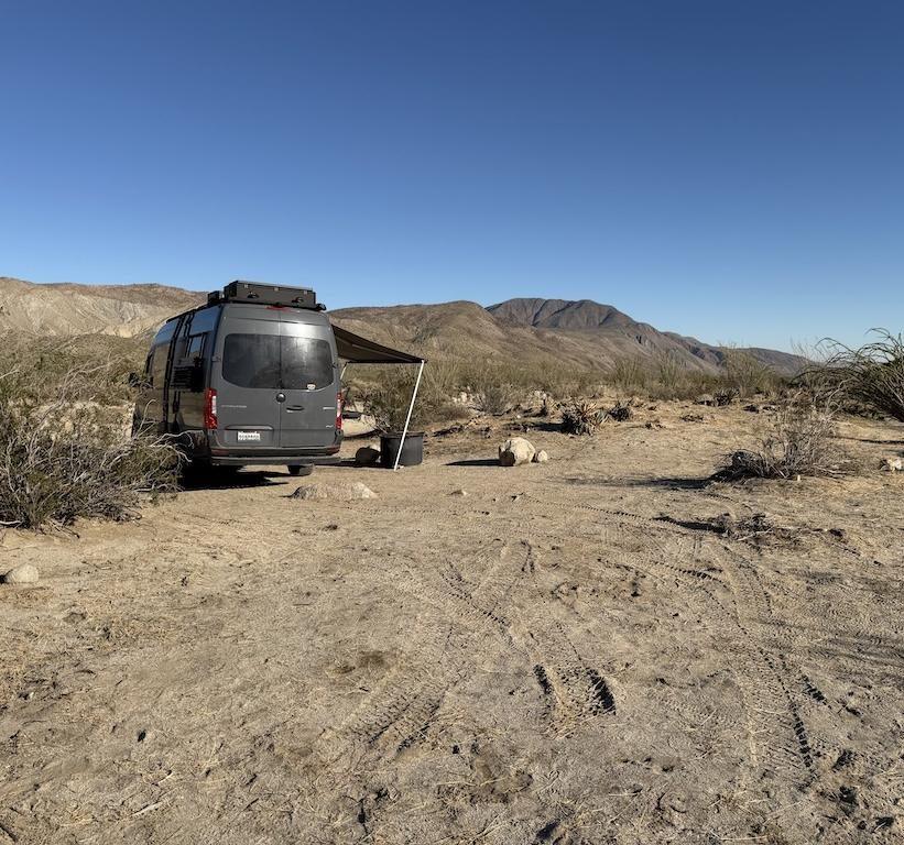 Man looking at Sprinter van parked off Coyote Canyon Road, at Anza-Borrego Desert State Park, California.