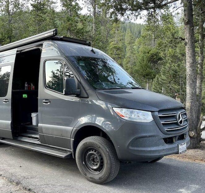 Man getting storage on top of Sprinter camper van at Madison Campground in Yellowstone National Park, Wyoming